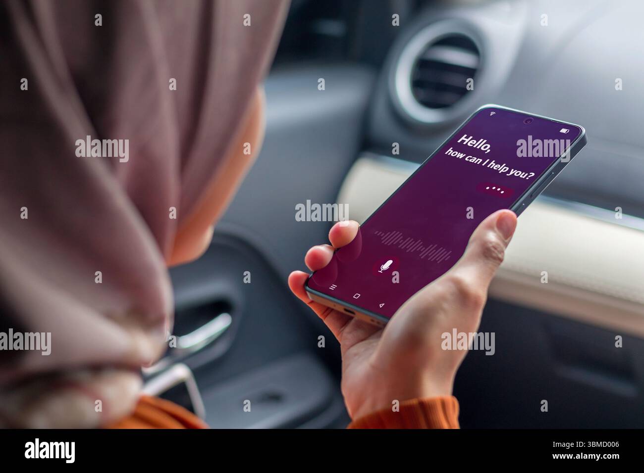 Une femme musulmane dans une voiture tenant un smartphone pour utiliser un assistant vocal virtuel Banque D'Images