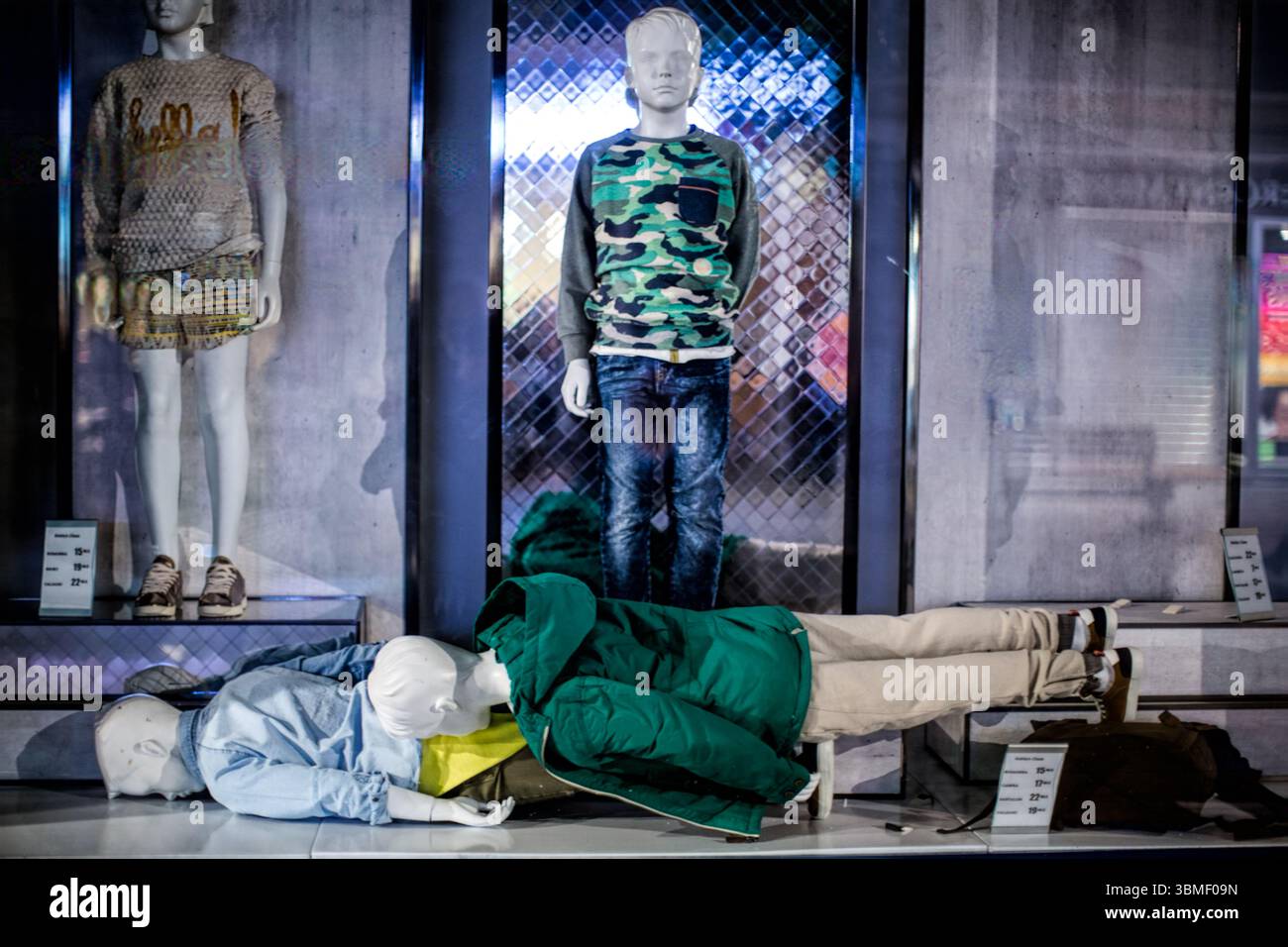 Les mannequins sont positionnés dans une vitrine, l'un debout et les autres dispersés. Les articles de mode semblent momentanément abandonnés. Banque D'Images