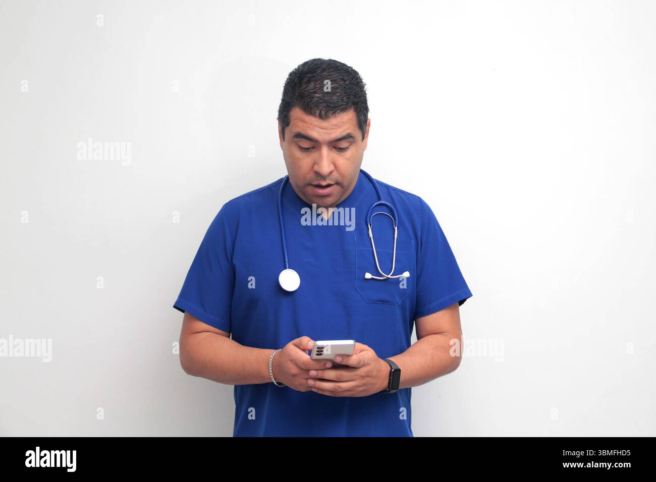Un médecin latino-américain à la peau foncée avec un stéthoscope montre son téléphone portable pour avoir des consultations en ligne avec ses patients Banque D'Images Un médecin latino-américain à la peau foncée avec un stéthoscope montre son téléphone portable pour avoir des consultations en ligne avec ses patients Banque D'Images