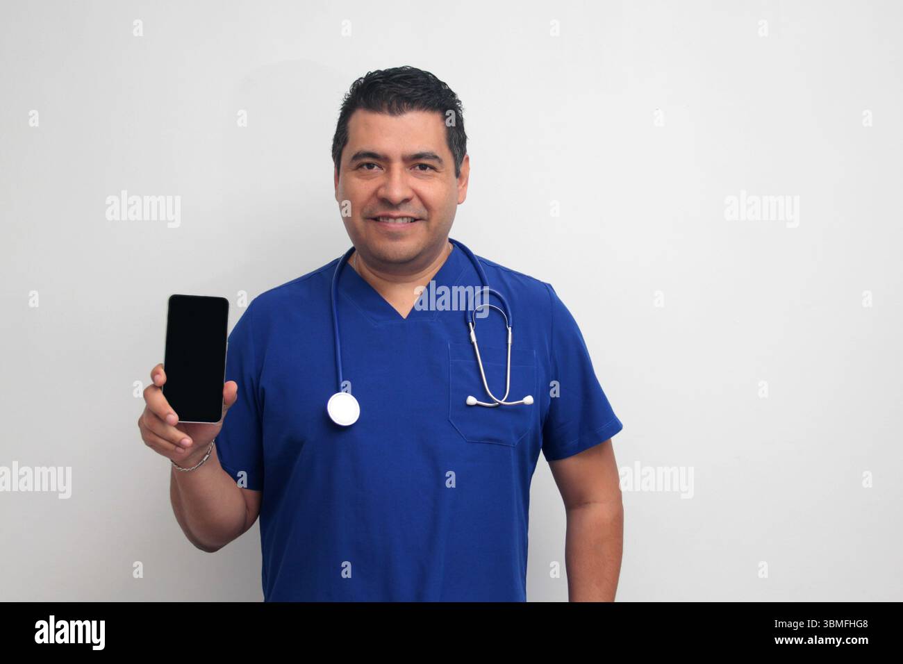 Un médecin latino-américain à la peau foncée avec un stéthoscope montre son téléphone portable pour avoir des consultations en ligne avec ses patients Banque D'Images Un médecin latino-américain à la peau foncée avec un stéthoscope montre son téléphone portable pour avoir des consultations en ligne avec ses patients Banque D'Images