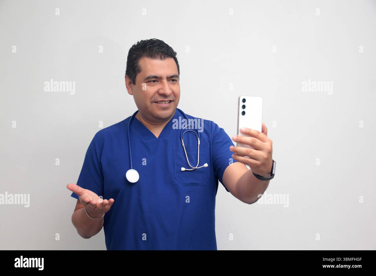 Un médecin latino-américain à la peau foncée avec un stéthoscope montre son téléphone portable pour avoir des consultations en ligne avec ses patients Banque D'Images Un médecin latino-américain à la peau foncée avec un stéthoscope montre son téléphone portable pour avoir des consultations en ligne avec ses patients Banque D'Images