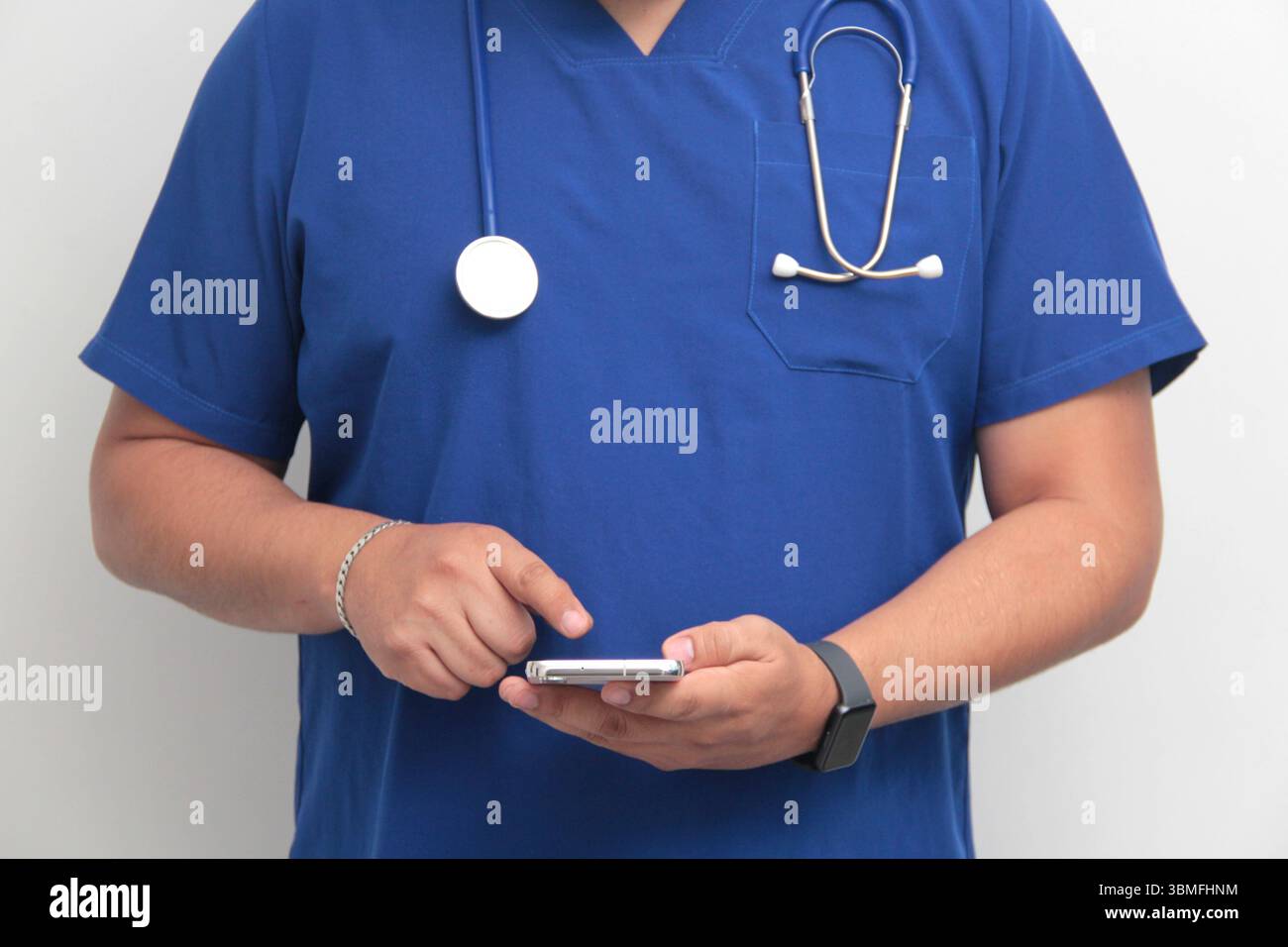 Un médecin latino-américain à la peau foncée avec un stéthoscope montre son téléphone portable pour avoir des consultations en ligne avec ses patients Banque D'Images Un médecin latino-américain à la peau foncée avec un stéthoscope montre son téléphone portable pour avoir des consultations en ligne avec ses patients Banque D'Images