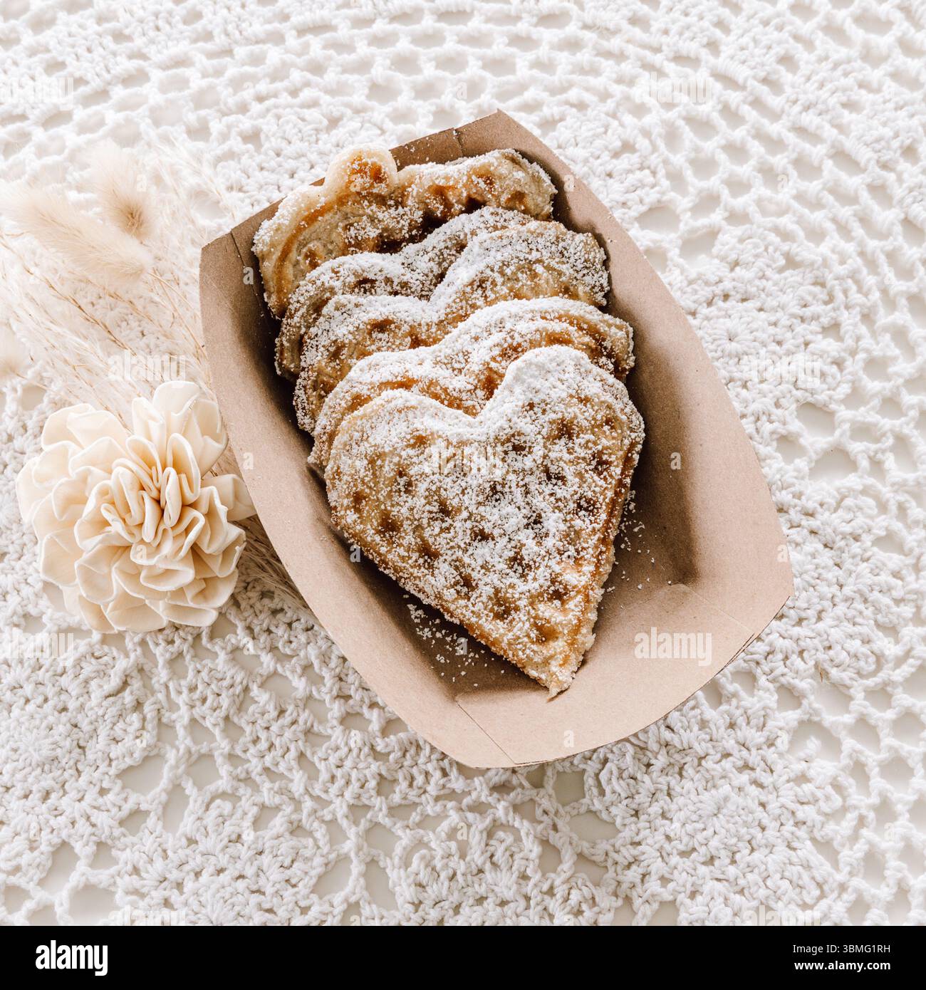 Gaufres en coeur fraîchement cuites, maison avec sucre en poudre dans un plateau artisanal, minimaliste, style vintage Banque D'Images