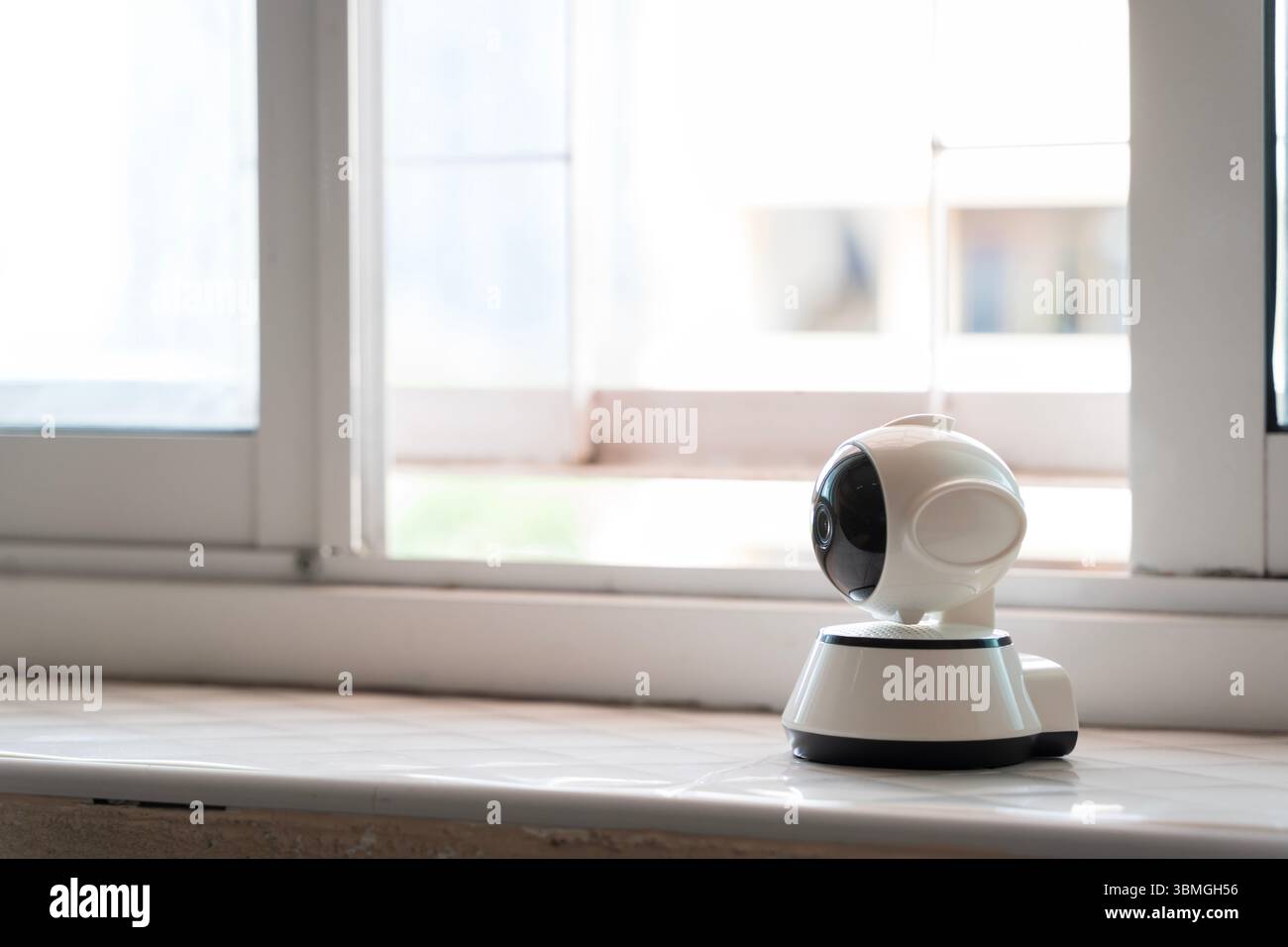 Caméra de sécurité intelligente moderne installée sur le rebord de la fenêtre intérieure pour la surveillance en temps réel, la sécurité, la surveillance à distance et la protection de la maison ou de la propriété. Banque D'Images