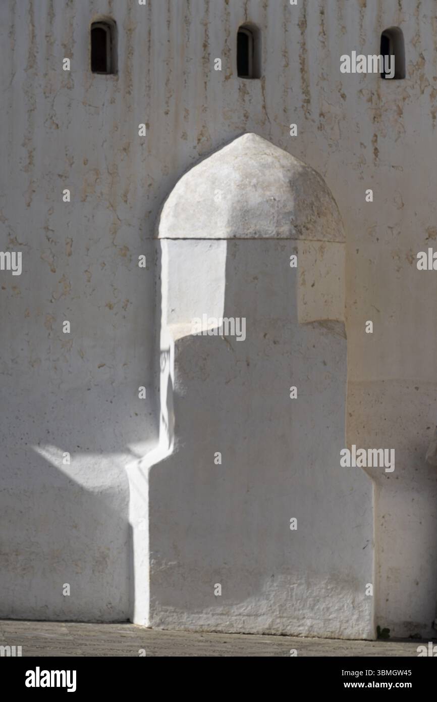 Hommes solitaires dans les djellabas d'hiver passant par la mosquée Saida, place Abdallah Guennoun, Asilah, Maroc, Afrique du Nord, Afrique Banque D'Images