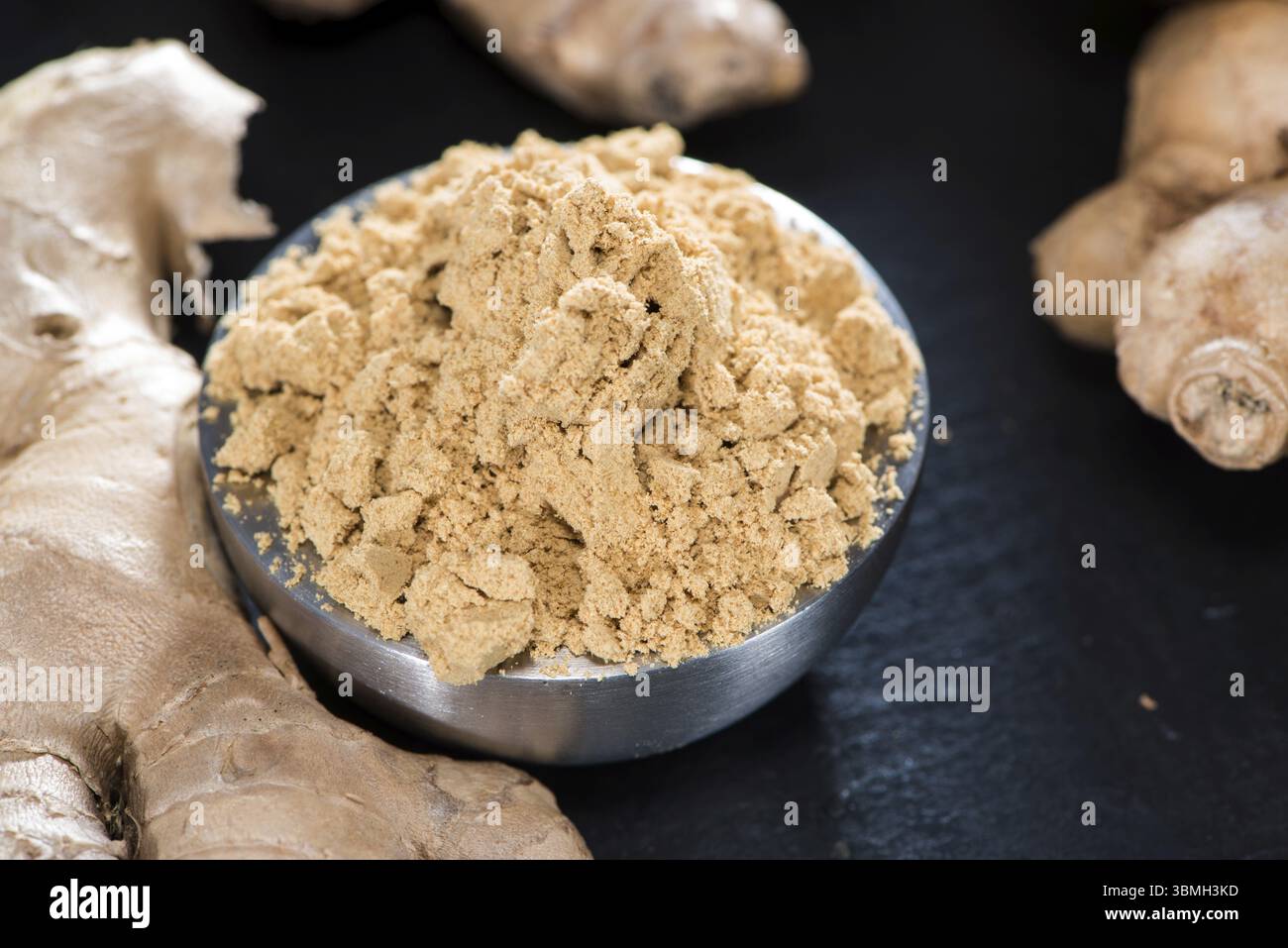 Petit bol avec du gingembre en poudre sur fond sombre Banque D'Images