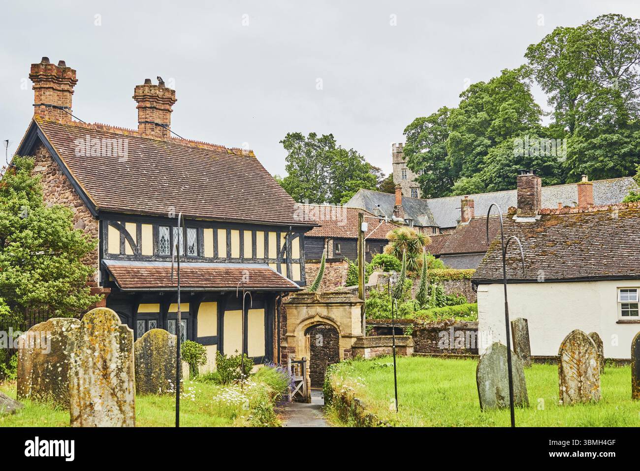 Maisons à colombages dans un village idyllique avec un cimetière et entouré d'arbres verts. Dunster et Dunster Castle, Minehead, Exmor, Angleterre, Great Banque D'Images