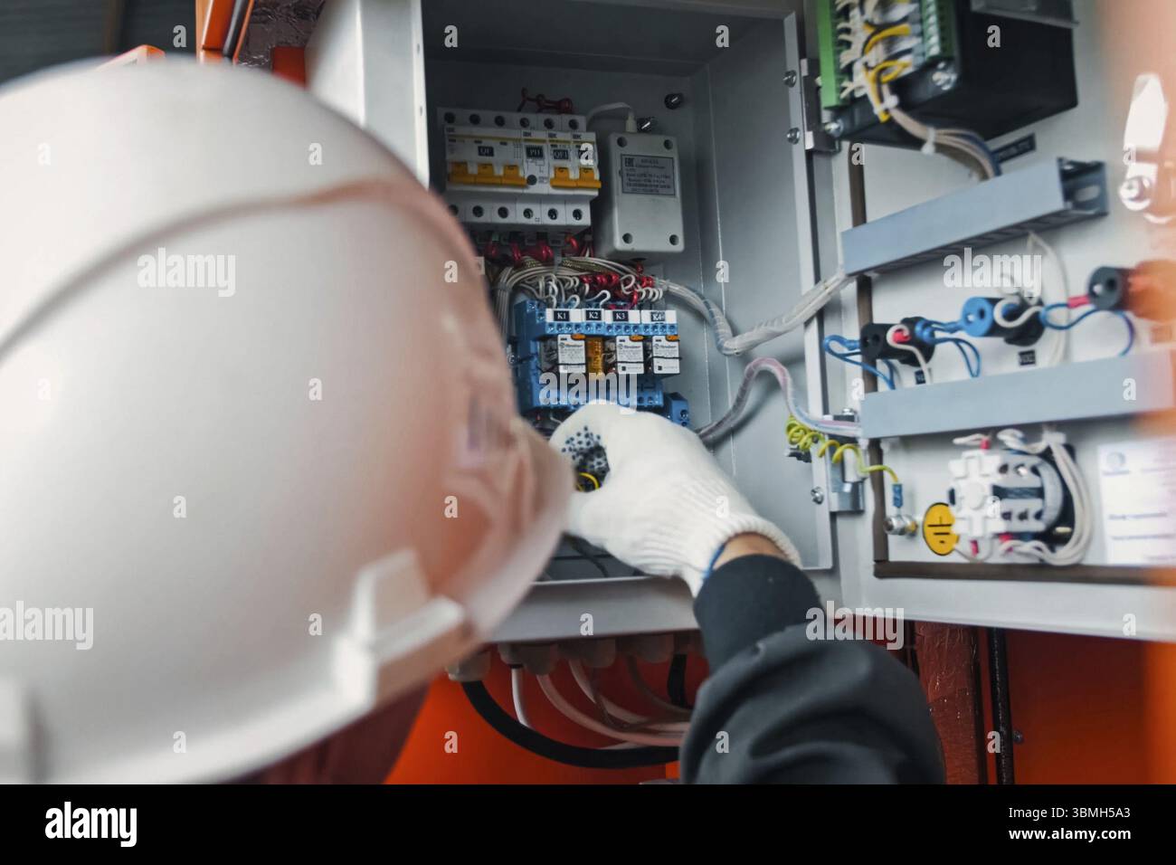 Travaux de réparation du volet électrique. L'électricien manipule l'équipement dans le volet électrique avec sa main dans le gant Banque D'Images