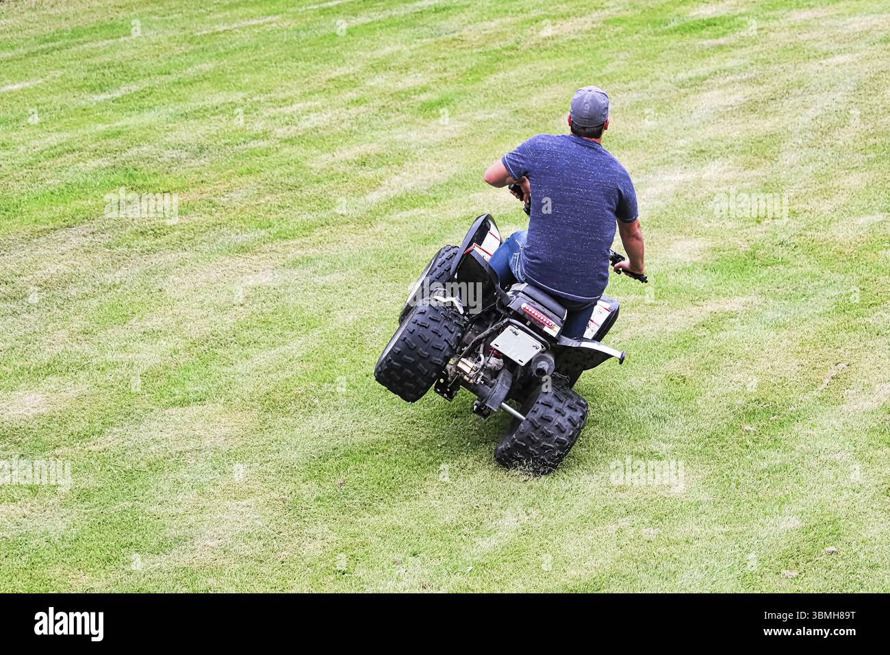 Le dos d'un adulte qui fait une cascade sur un quad pour enfants Banque D'Images Le dos d'un adulte qui fait une cascade sur un quad pour enfants Banque D'Images
