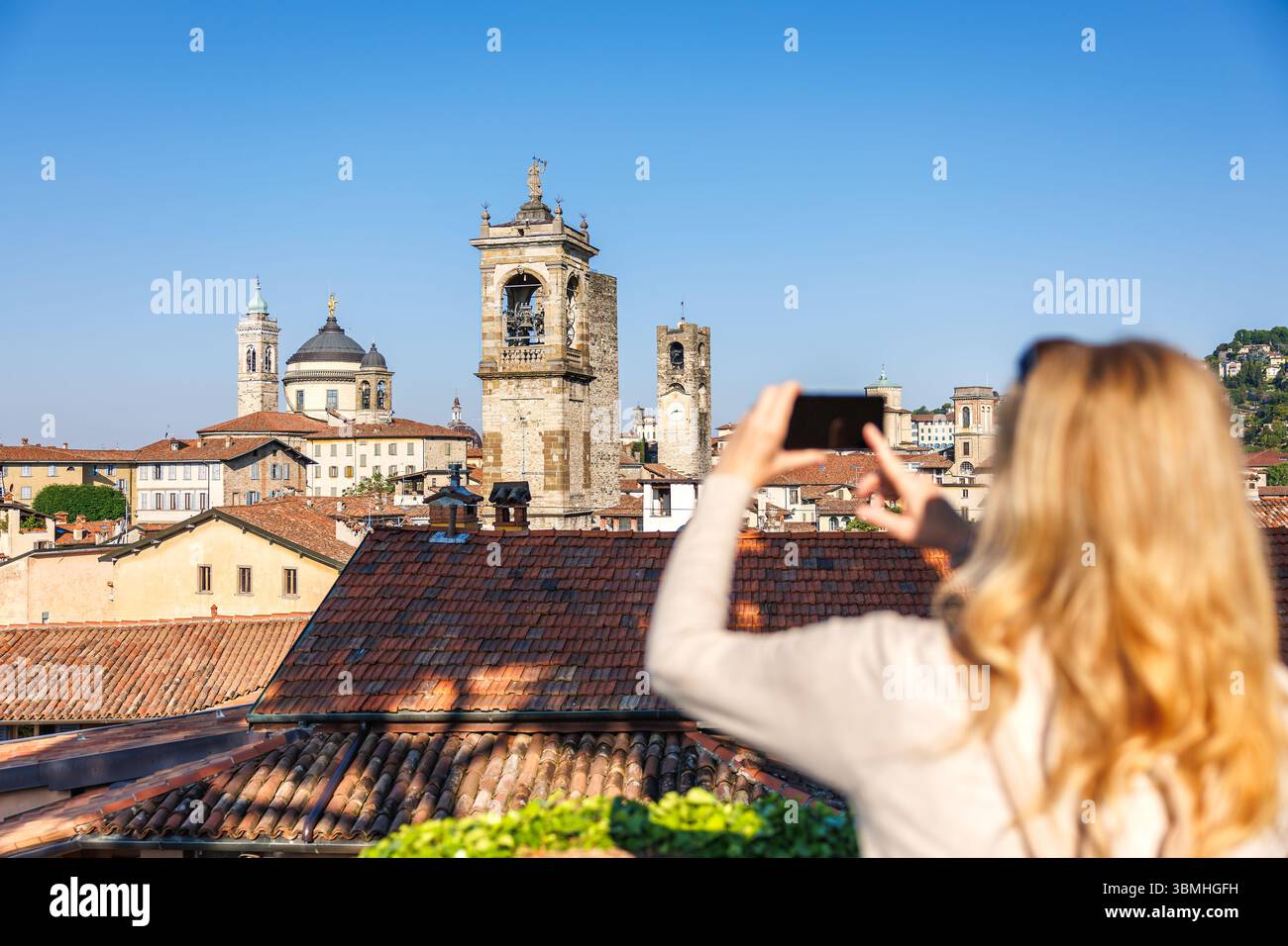 Femme touriste prenant photo sur téléphone portable ville skyline avec tours d'église à Citta Alta, Bergame, Italie pendant le voyage de vacances d'été Banque D'Images