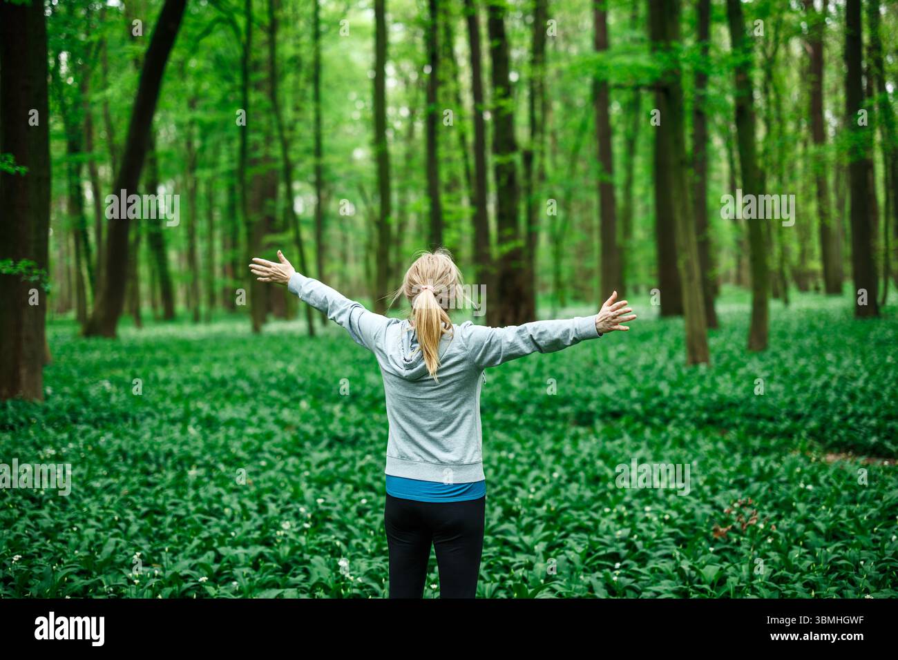Athlète femme célébrant la liberté avec les bras grands ouverts dans la nature, symbole de détente et de bien-être mental. Baignade en forêt Banque D'Images
