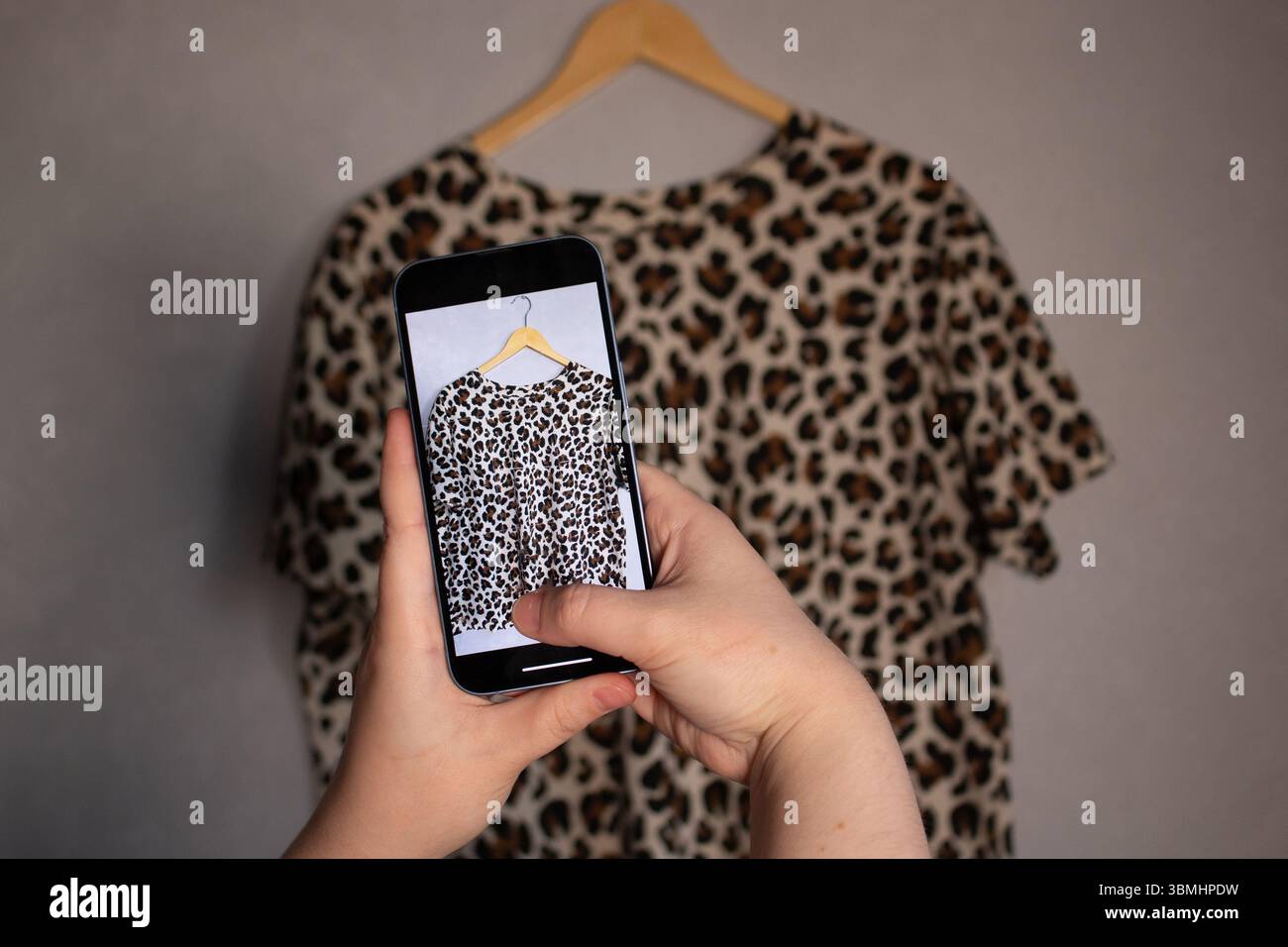 Fille prend des photos de ses vieux articles de garde-robe pour vendre d'occasion. Fond minimaliste. Concentrez-vous sur les habitudes de consommation respectueuses de l'environnement. Banque D'Images Fille prend des photos de ses vieux articles de garde-robe pour vendre d'occasion. Fond minimaliste. Concentrez-vous sur les habitudes de consommation respectueuses de l'environnement. Banque D'Images