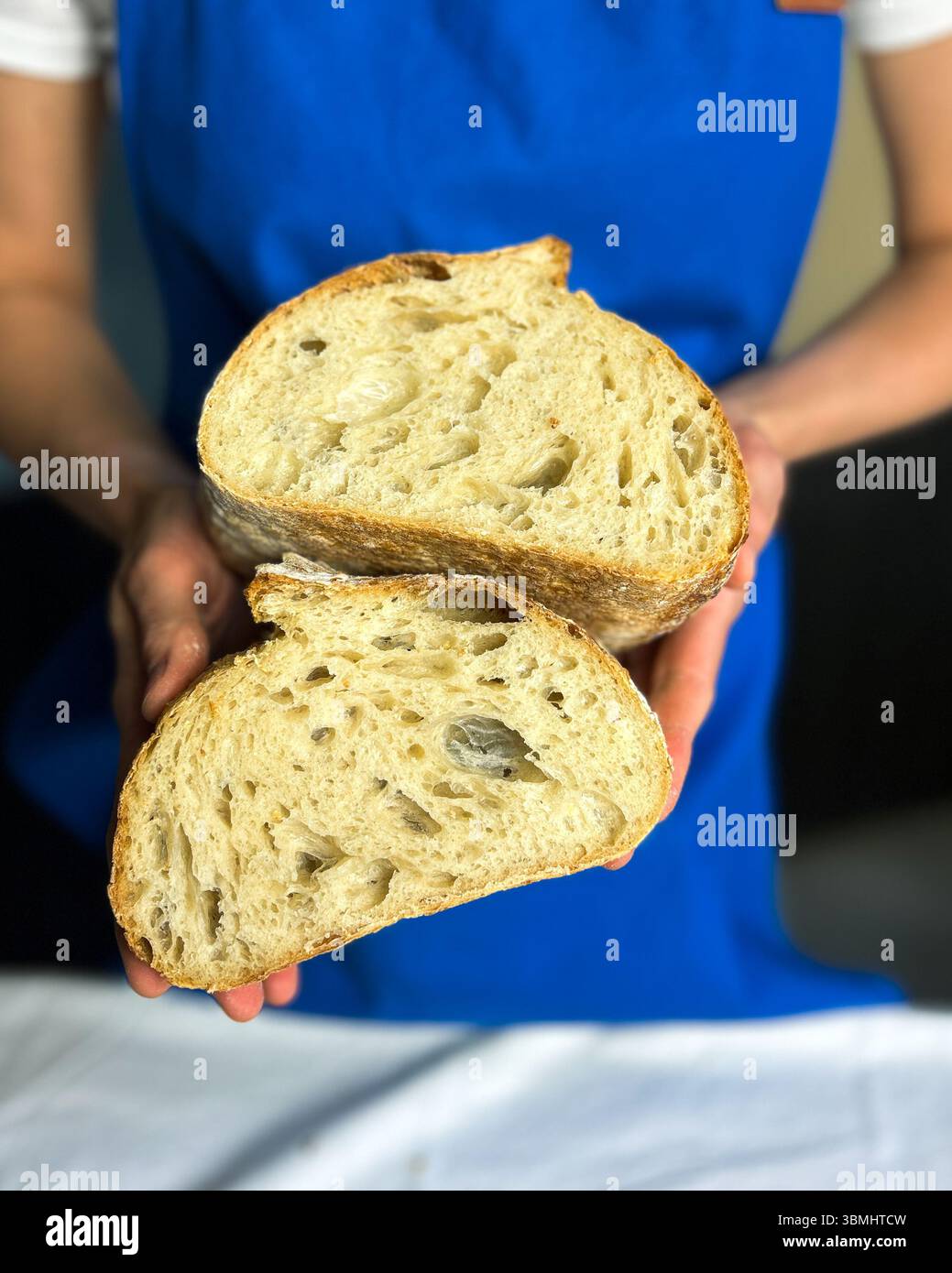 Femme tenant un pain de levain fraîchement cuit au four fait avec du starter sans gluten. Parfait pour les blogs de cuisson saine, les marques d'aliments biologiques et la boulangerie artisanale Banque D'Images
