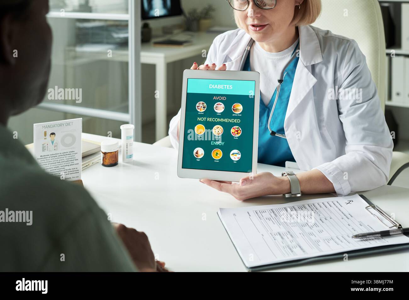 Médecin féminin caucasien d'âge moyen montrant un comprimé numérique avec des recommandations diététiques de diabète à l'homme noir d'âge moyen pendant la consultation médicale Banque D'Images