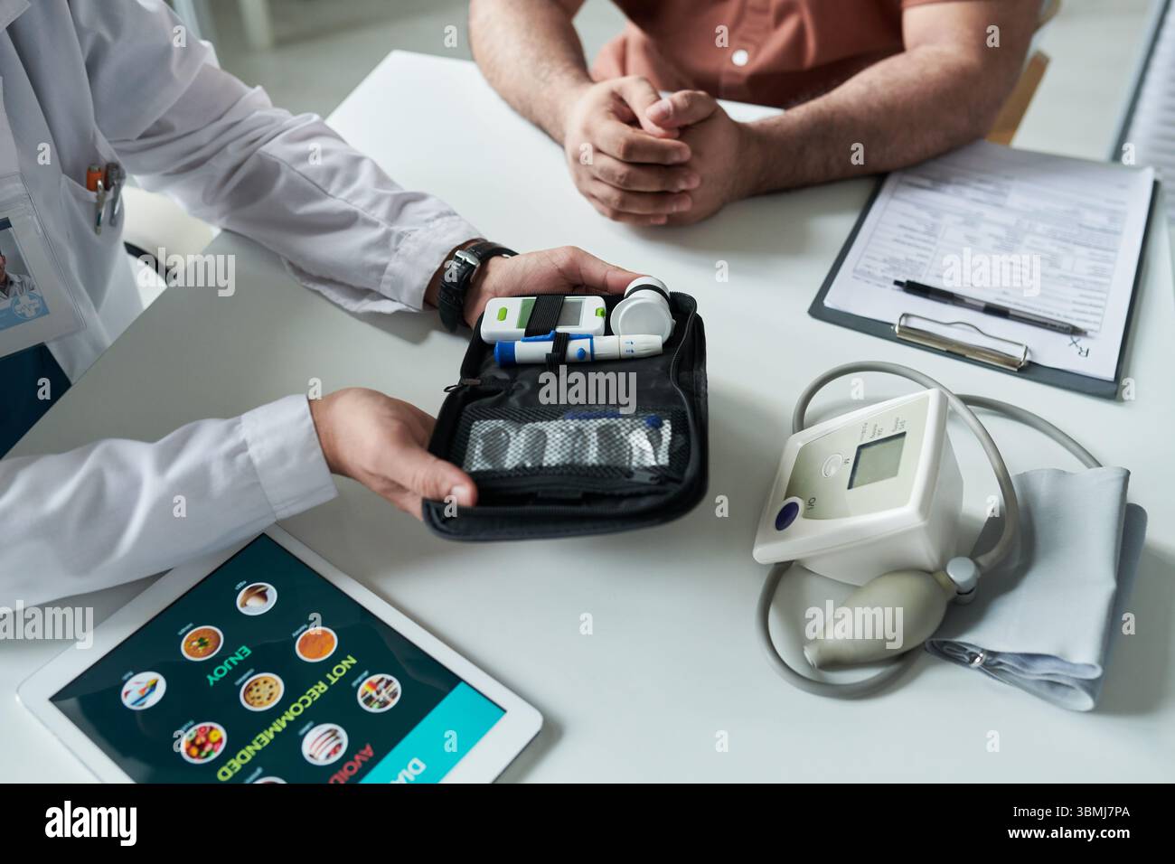 Homme caucasien d'âge moyen assis au bureau avec les mains pliées tandis que le médecin montrant le kit de gestion du diabète, y compris le glucomètre et le stylo à insuline pendant M. Banque D'Images