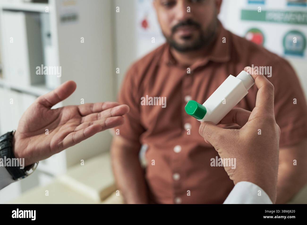Homme caucasien d'âge moyen assis dans le cabinet médical consultant avec le médecin, médecin tenant l'inhalateur et expliquant l'utilisation, patient écoutant attentivement Banque D'Images