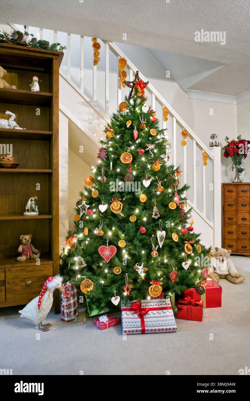 Sapin de Noël décoré dans un thème rustique avec des tranches d'orange, des boules de rotin et des décorations en forme de cœur et des cadeaux en dessous dans le cadre de la maison Banque D'Images