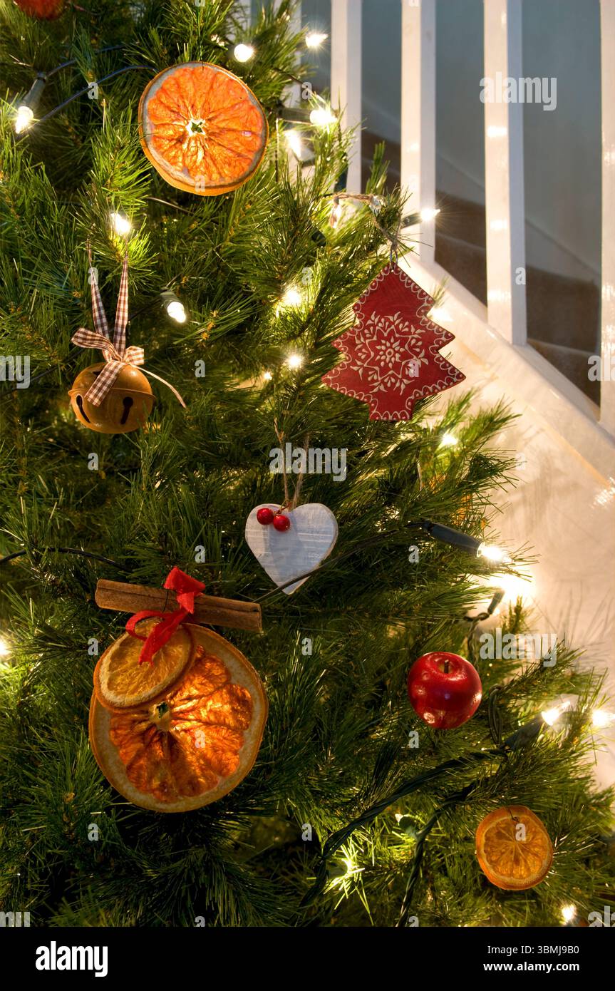 Sapin de Noël décoré dans un thème rustique de tranches d'orange, ornements en bois et fausses pommes, montrant l'arbre de noël partiel Banque D'Images