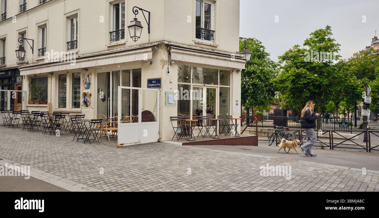 Femme promenant le chien devant le café parisien dans la matinée Banque D'Images