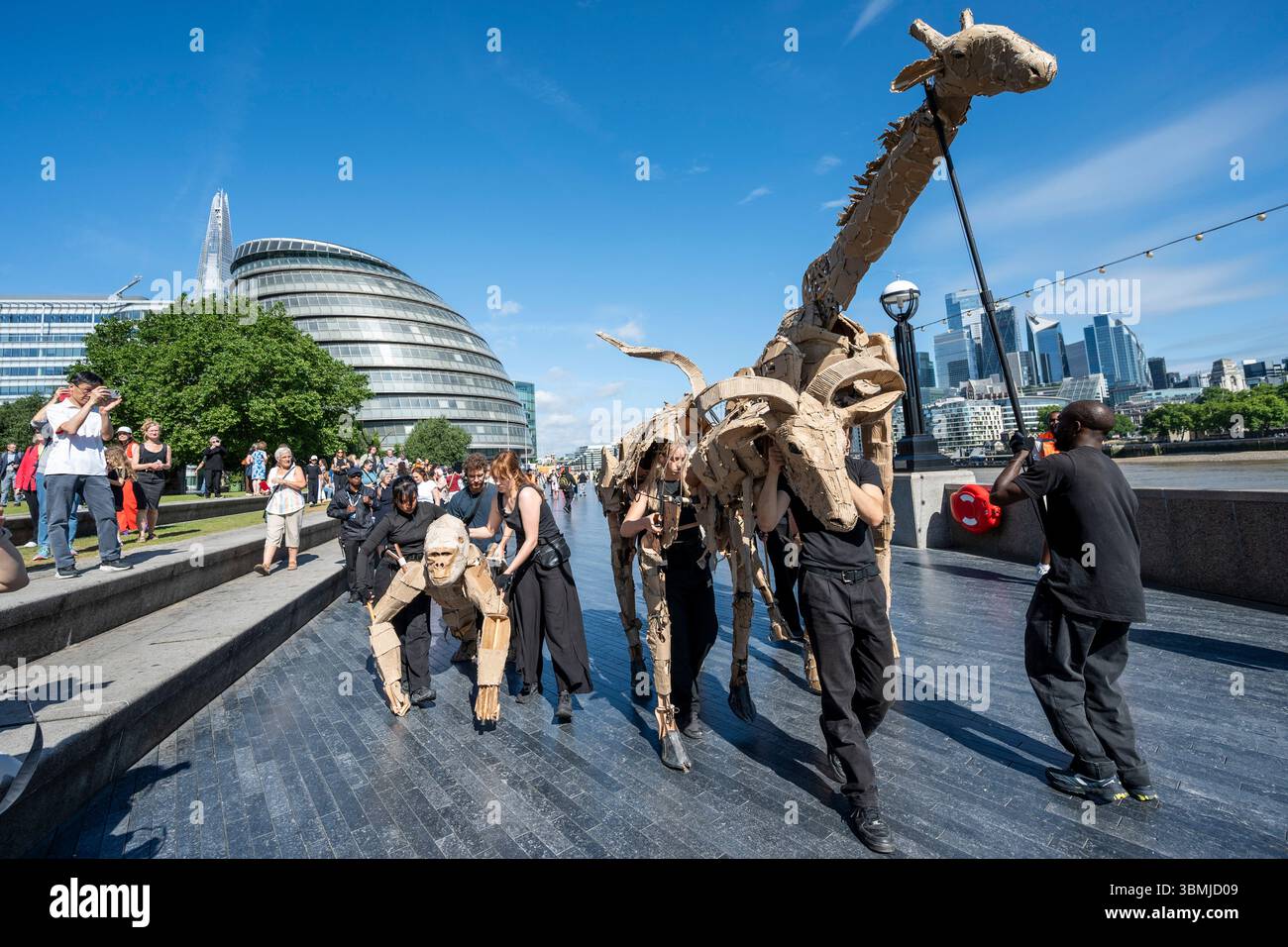 Londres, Royaume-Uni. 27 juin 2025. Les marionnettistes se produisent lors d’une conférence téléphonique près de Tower Bridge for THE HERDS, une nouvelle œuvre d’art majeure qui voit des animaux marionnettes grandeur nature voyager, d’avril à août 2025, sur une route de 20 000 km entre le bassin du Congo et le cercle arctique, symbolisant leur fuite d’une catastrophe climatique. Gorilles, lions, zèbres et kudus sont arrivés à Londres pour le week-end avant de passer à Manchester. Credit : Stephen Chung / Alamy Live News Banque D'Images