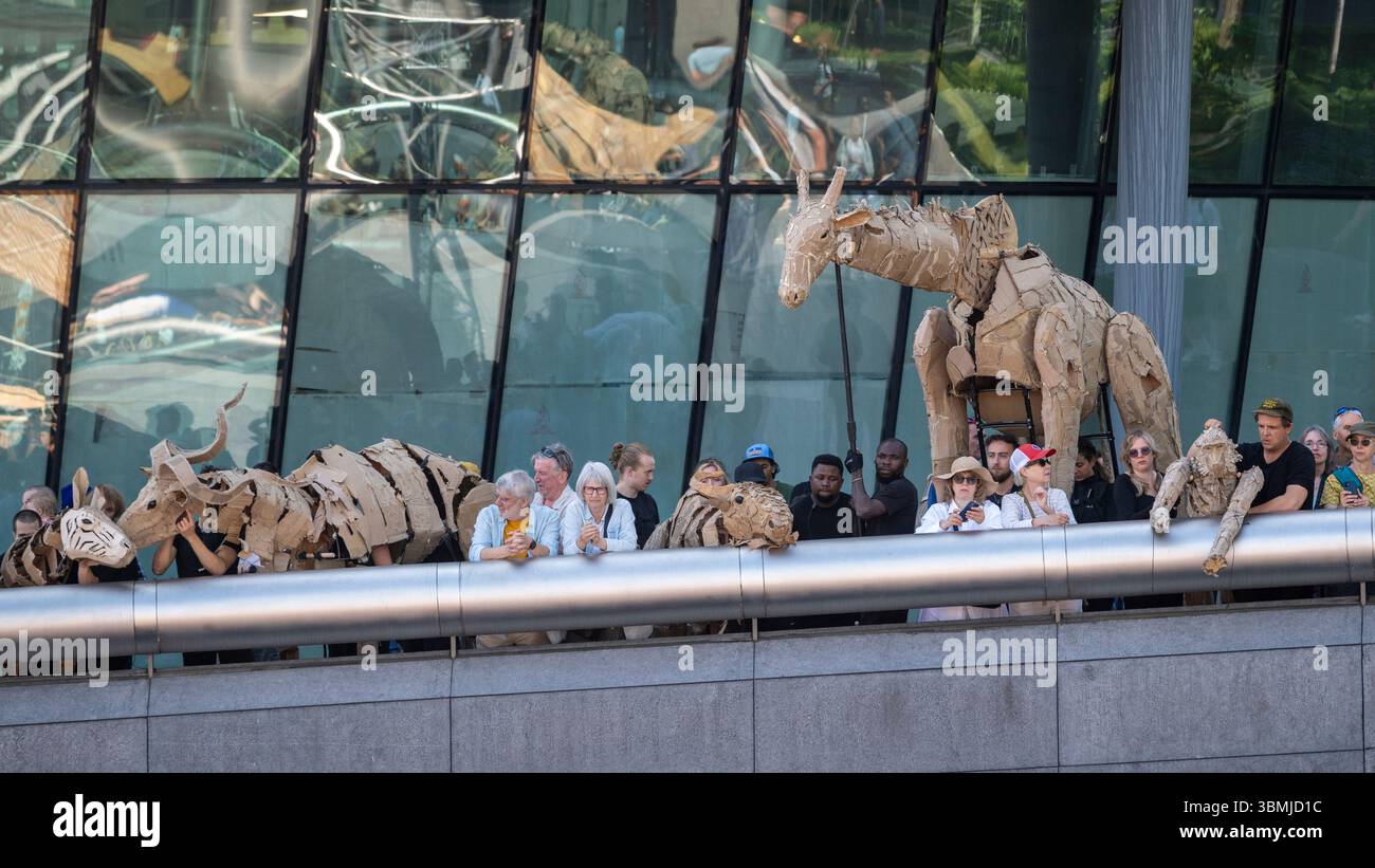 Londres, Royaume-Uni. 27 juin 2025. Les marionnettistes se produisent lors d’une conférence téléphonique près de Tower Bridge for THE HERDS, une nouvelle œuvre d’art majeure qui voit des animaux marionnettes grandeur nature voyager, d’avril à août 2025, sur une route de 20 000 km entre le bassin du Congo et le cercle arctique, symbolisant leur fuite d’une catastrophe climatique. Gorilles, lions, zèbres et kudus sont arrivés à Londres pour le week-end avant de passer à Manchester. Credit : Stephen Chung / Alamy Live News Banque D'Images