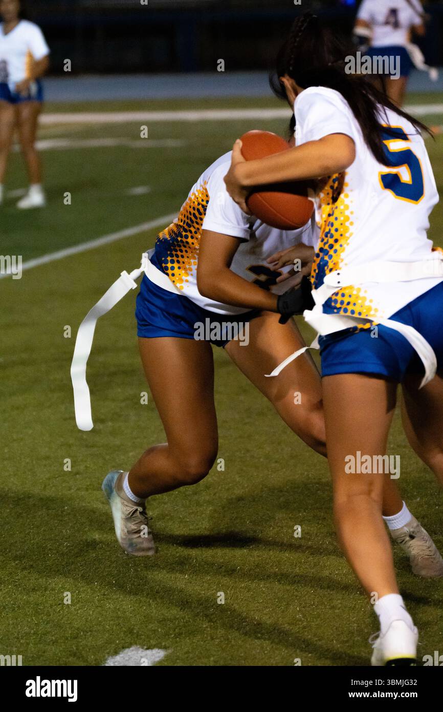 Jeu de football drapeau de la jeunesse avec des équipes bleues et blanches jouant sur un terrain herbeux, des enfants en compétition dans les sports sous le ciel ensoleillé, travail d'équipe athlétique, Banque D'Images