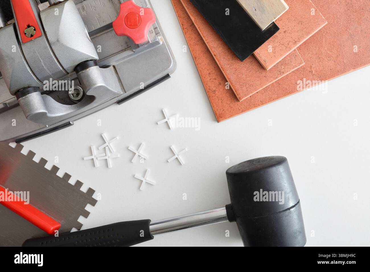 Détail du coupe-carreaux et des carreaux coupés sur la table blanche avec spatule de truelle et entretoises. Vue de dessus. Banque D'Images