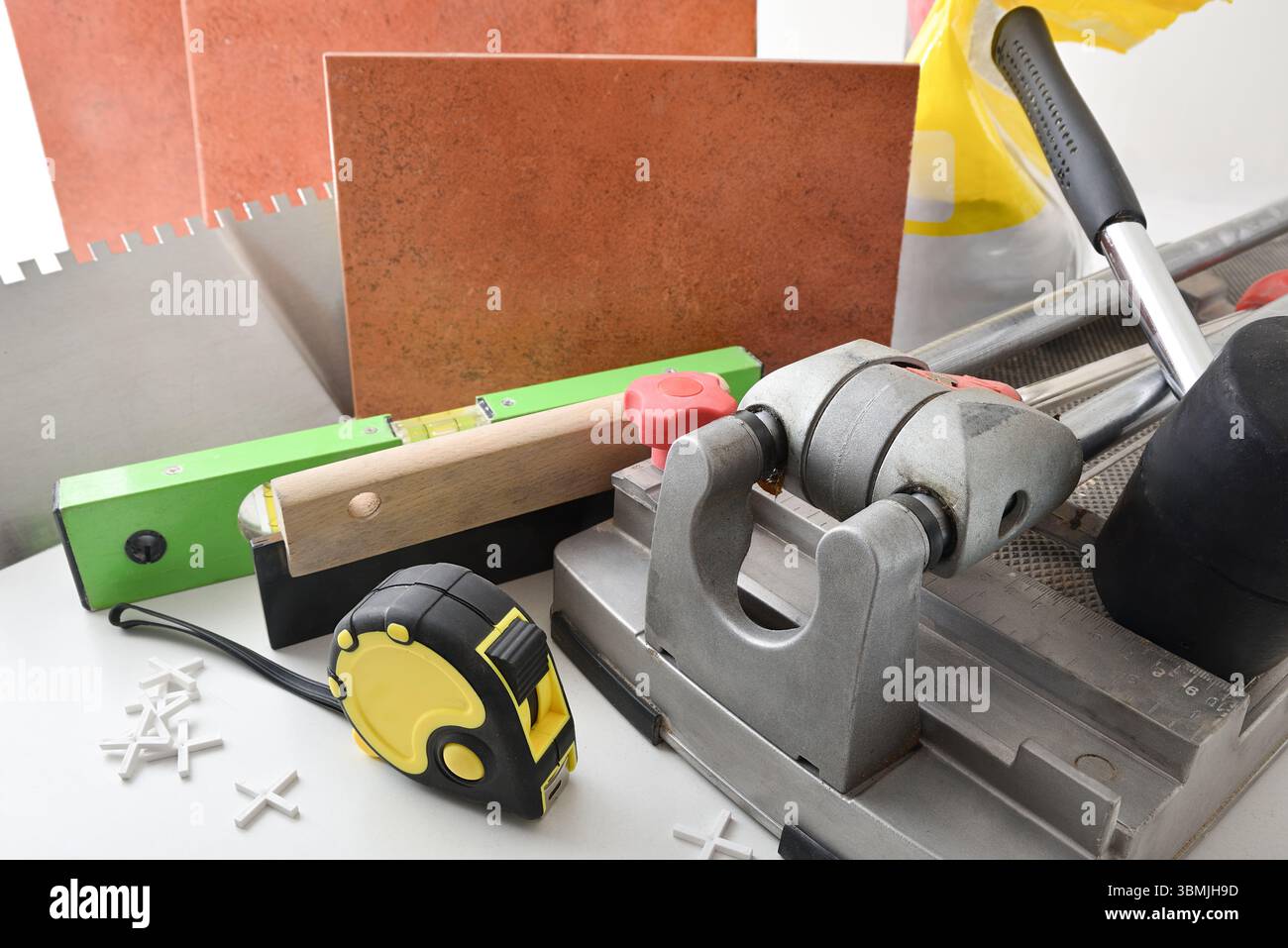 Fourniture d'outils et de matériel de carrelage sur table blanche et mur carrelé. Vue surélevée. Banque D'Images