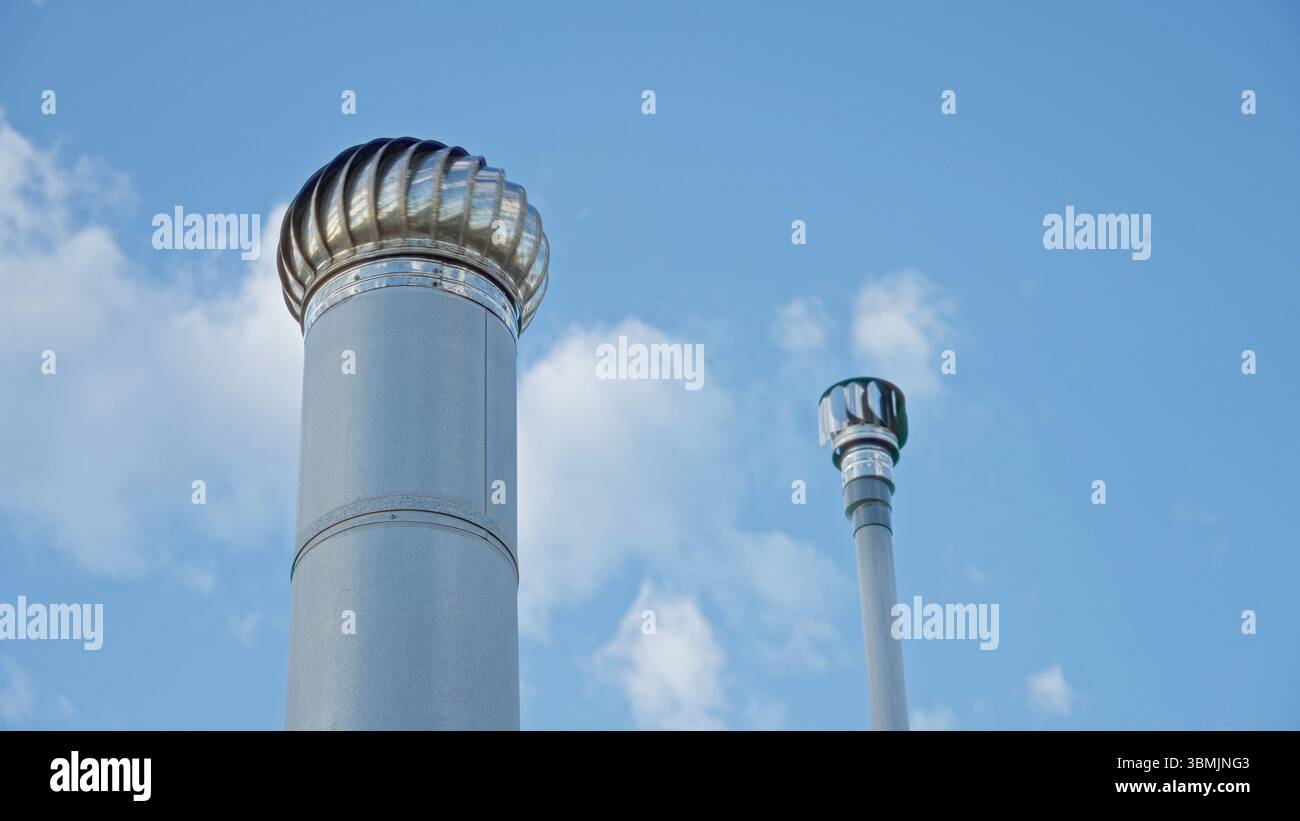 Cheminées en métal vibrantes contre un ciel bleu clair sur un toit-terrasse présentant un design architectural moderne et des caractéristiques de style industriel dans un environnement urbain Banque D'Images