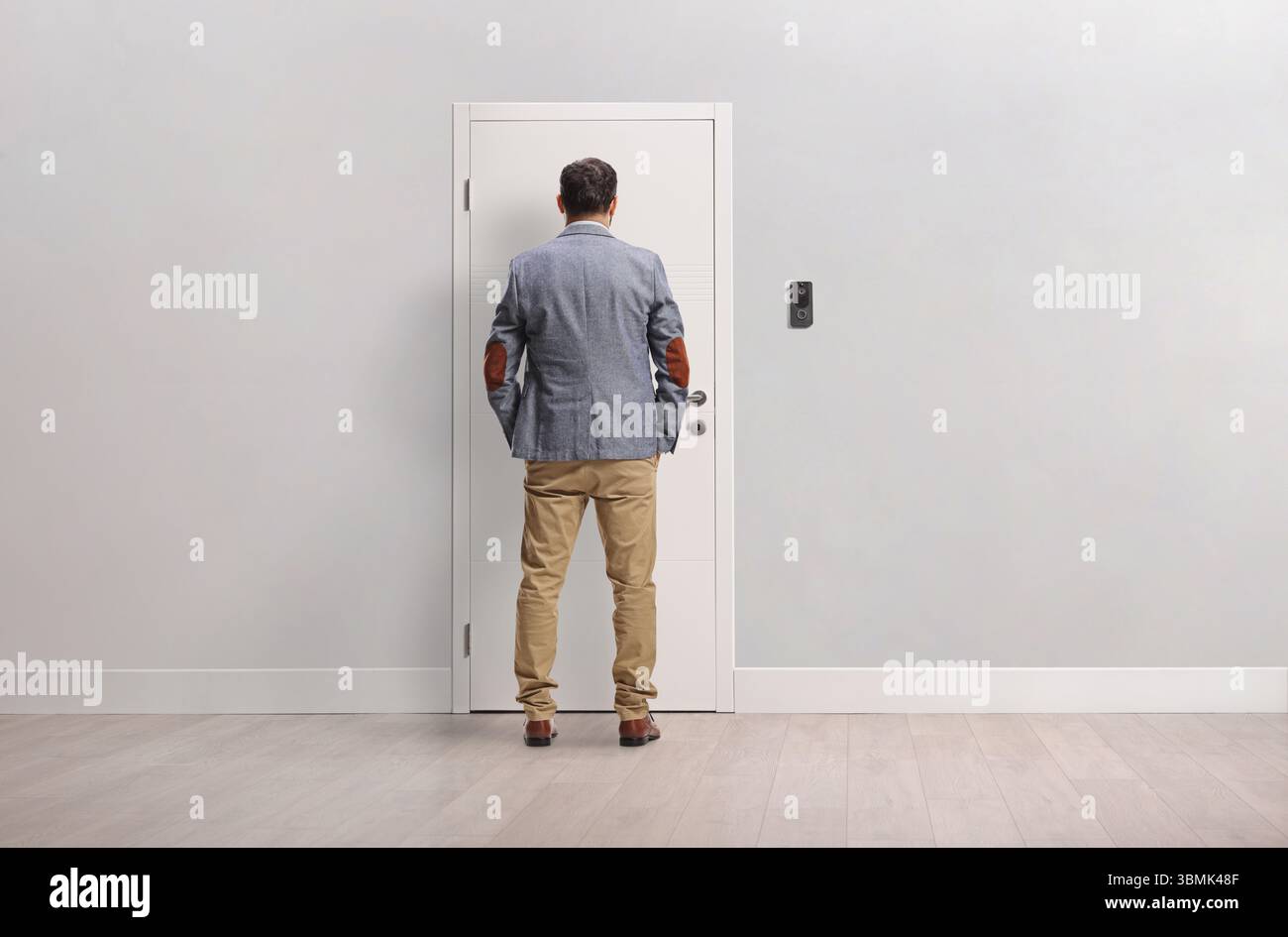 Vue arrière d'un homme debout devant une porte d'appartement Banque D'Images