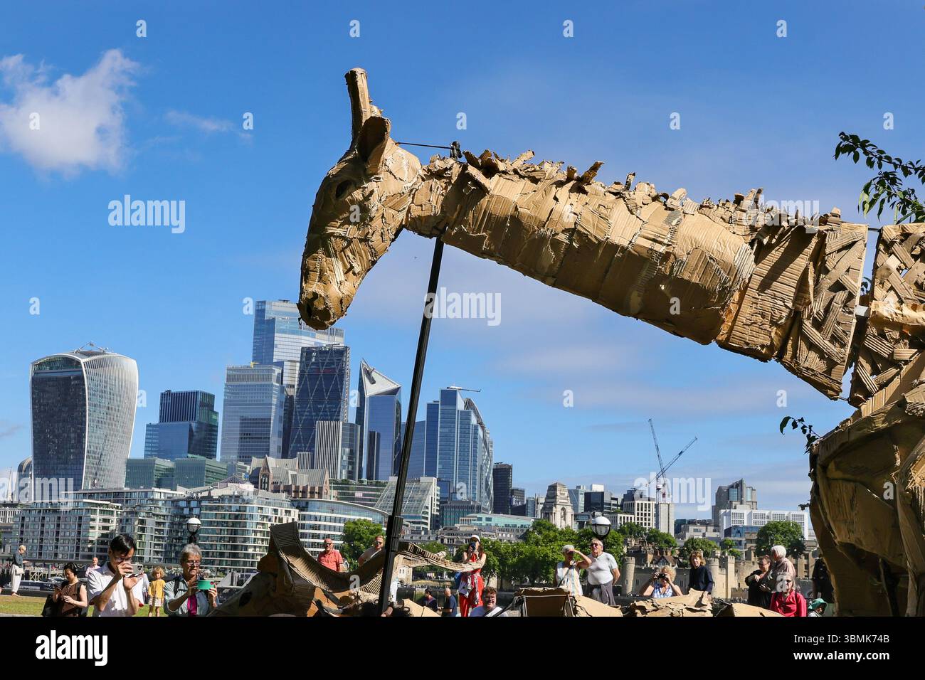 Londres, Royaume-Uni. 27 juin 2025. Les artistes marchent du Bridge Theatre à la Tamise avec Tower Bridge et la City de Londres derrière. LES TROUPEAUX sont l'art public et l'action climatique. D’avril à août 2025, les animaux marionnettes grandeur nature parcourent un itinéraire de 20 000 km entre le bassin du Congo et le cercle arctique, symbolisant leur fuite de la catastrophe climatique avec des arrêts dans de nombreuses villes et pays, à Londres du 27 au 29 juillet. Crédit : Imageplotter/Alamy Live News Banque D'Images