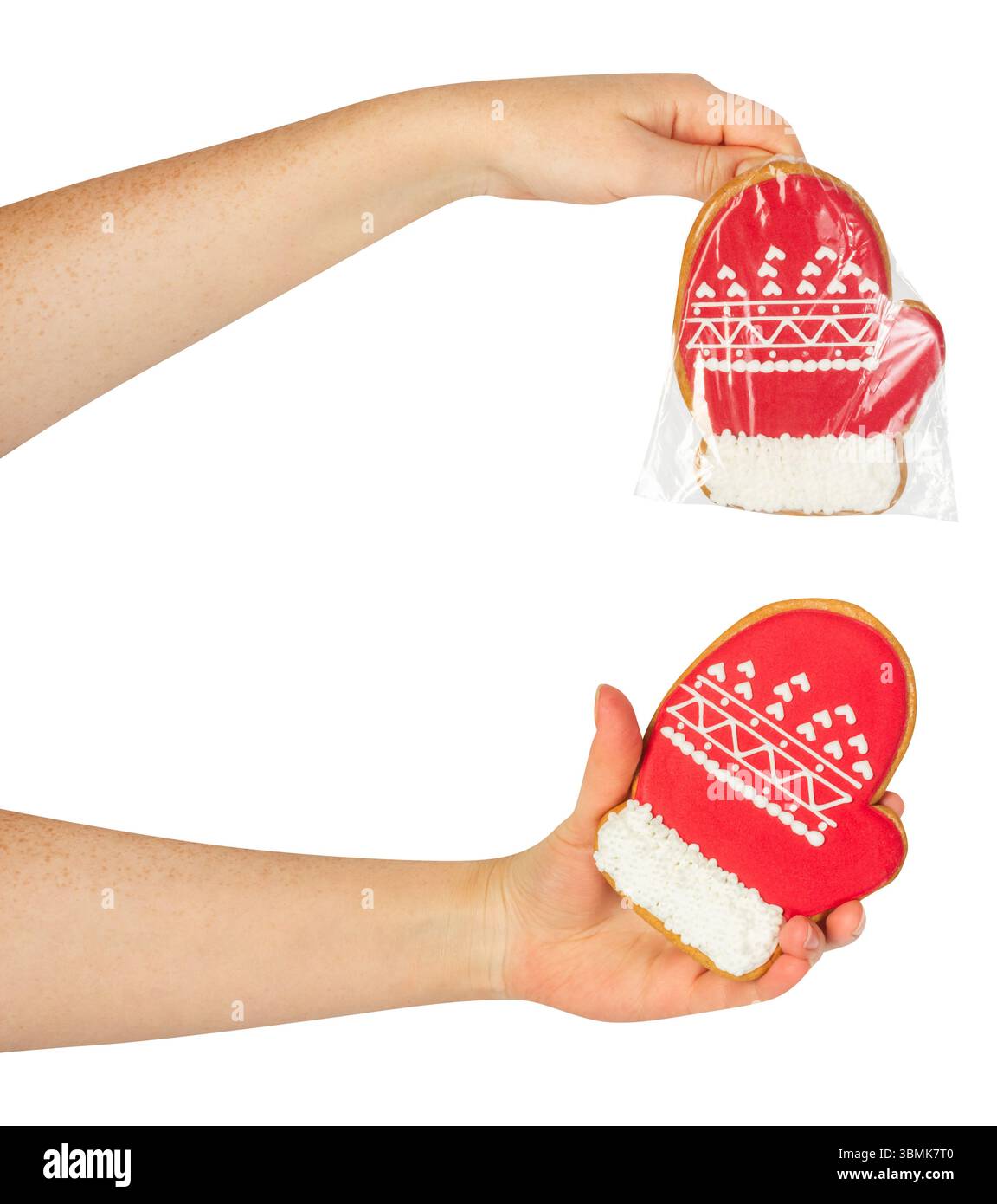 Photo isolée de la main féminine tenant des biscuits de pain d'épice emballés de noël ou du nouvel an en forme de gant de père noël sur fond blanc. Banque D'Images