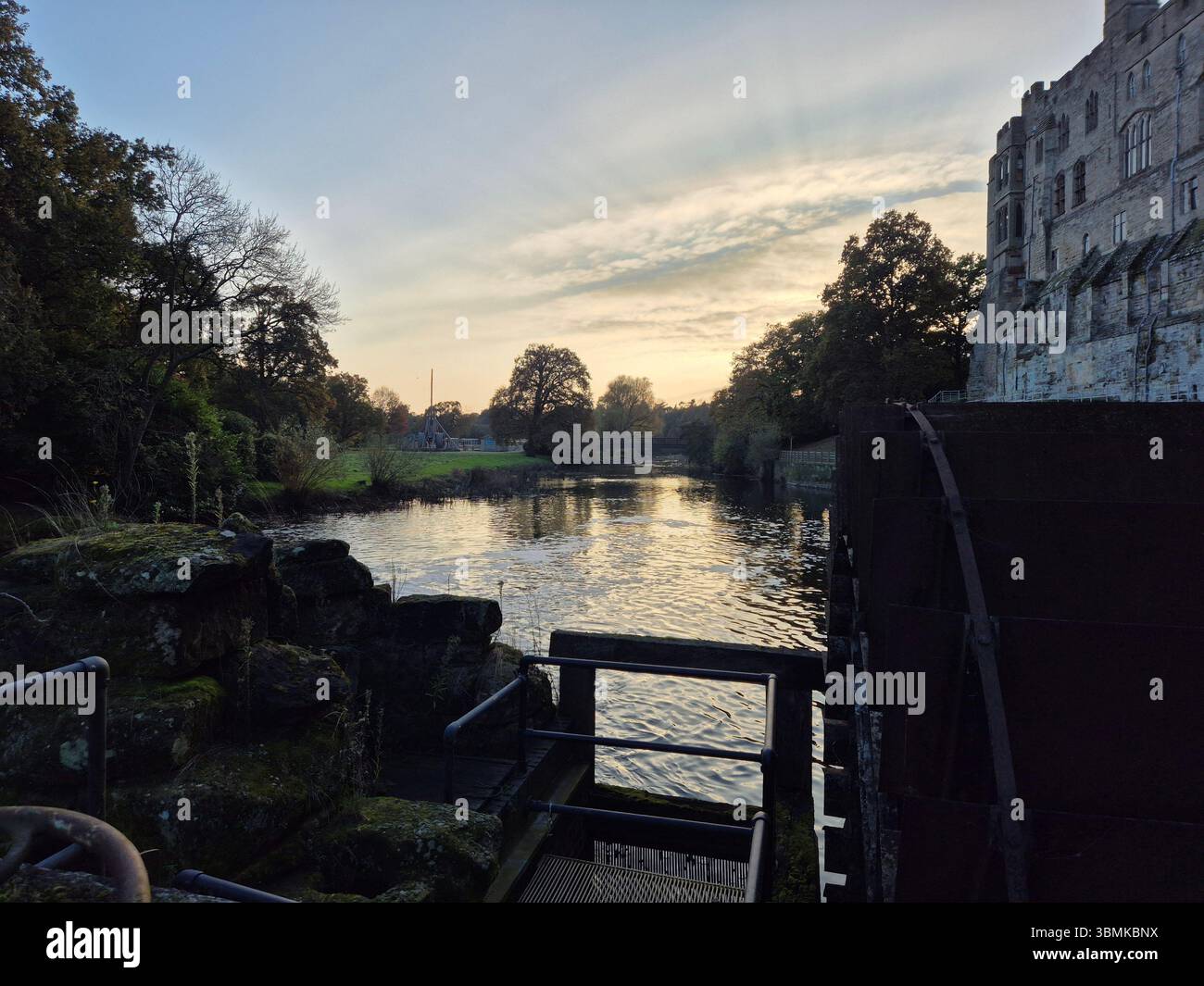 Vue sur le coucher du soleil à côté de la rivière Avon et les murs du château de Warwick à Warwick, Warwickshire, Angleterre. - Image de stock capturée avec un smartphone