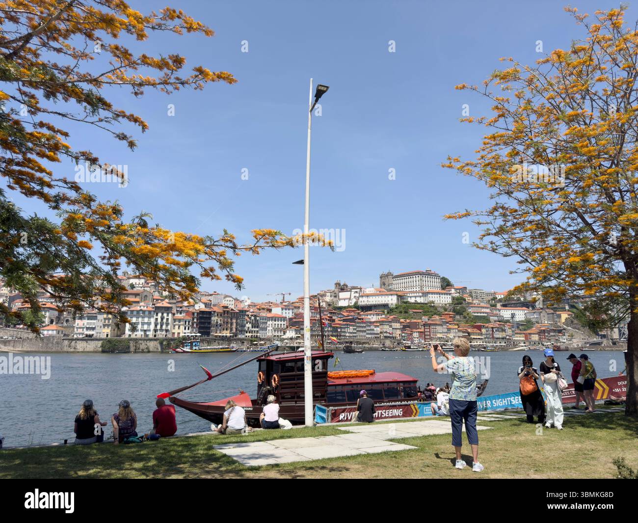 Les touristes s'assoient et apprécient la vue sur le fleuve Douro de Vila Nova de Gaia à Porto, Portugal - Image de stock capturée avec un smartphone