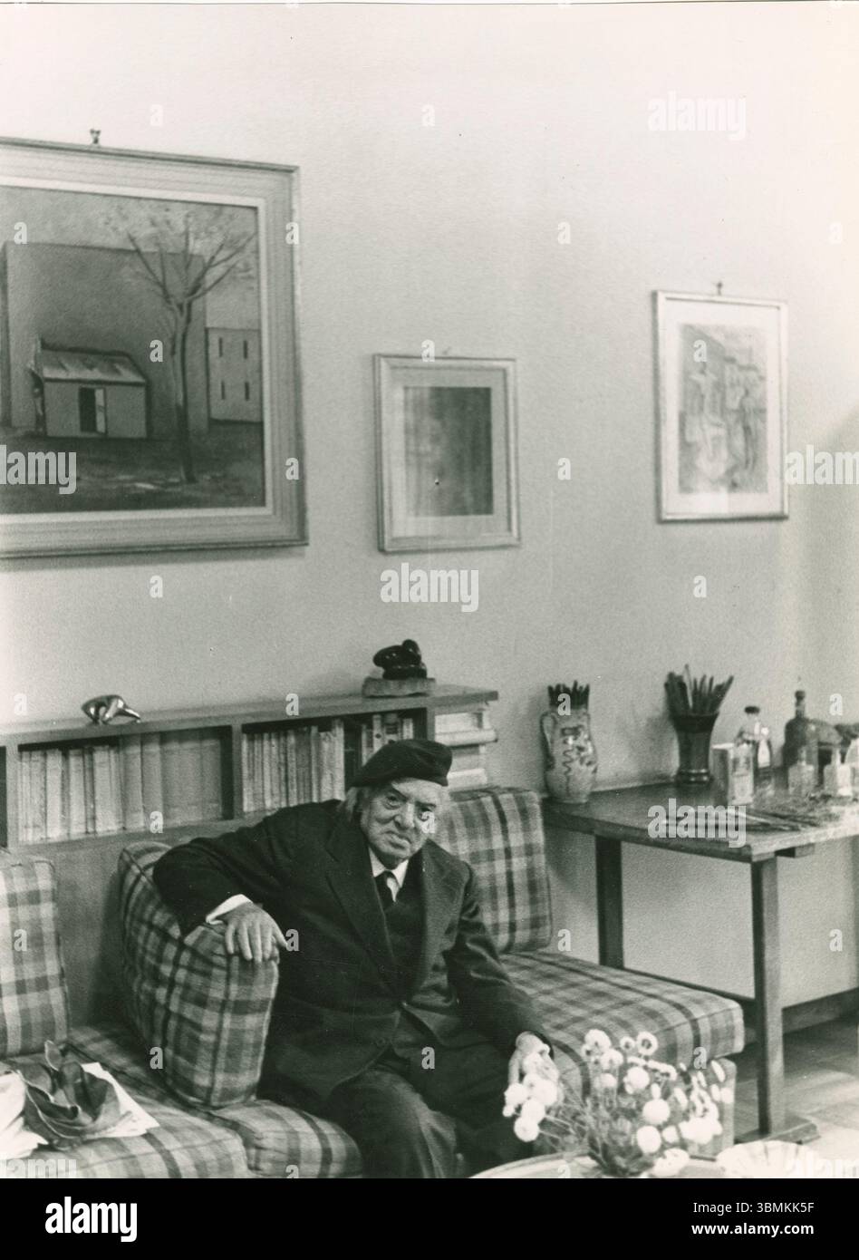 Le peintre italien Carlo Carrà assis sur le canapé dans le studio-salle à manger de sa maison sur la via Sandro Sandri à Milan. Banque D'Images