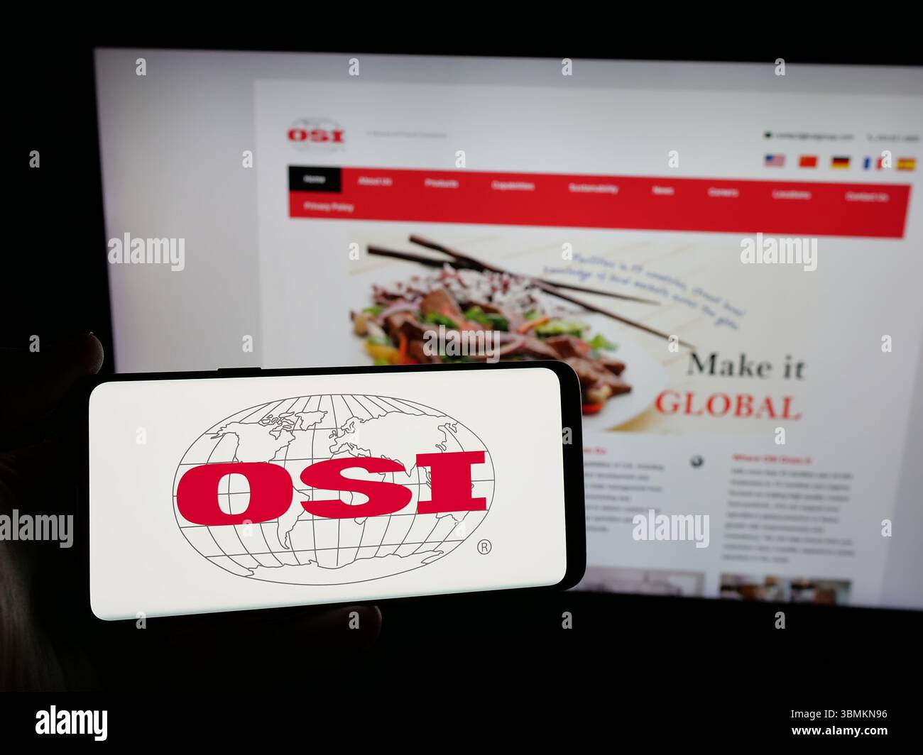 Stuttgart, Allemagne - 05-02-2025 : personne tenant un smartphone avec le logo de la société américaine de transformation de viande OSI Group LLC sur l'écran en face du site Web. Banque D'Images