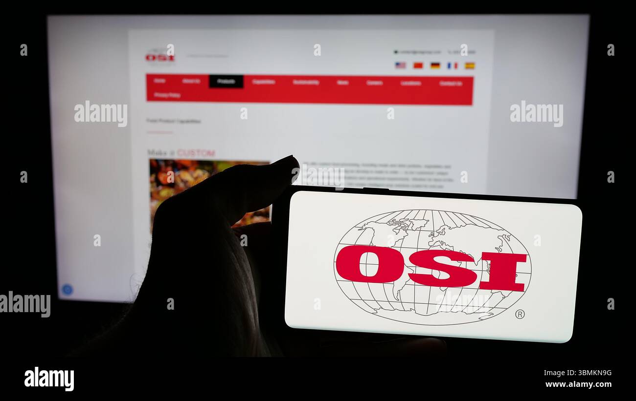 Stuttgart, Allemagne - 05-02-2025 : personne tenant un téléphone portable avec le logo de la société américaine de transformation de viande OSI Group LLC sur l'écran en face de la page Web. Banque D'Images