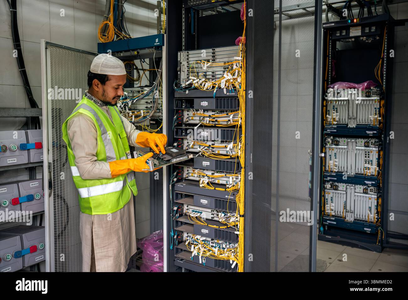 Techniciens et ingénieurs réparant les périphériques réseau, les routeurs, configurant les serveurs et réparant les câbles dans la salle réseau. Maintenance INFORMATIQUE Banque D'Images
