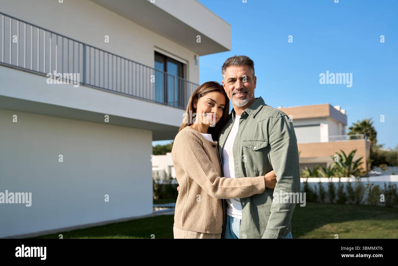 Portrait de couples familiaux matures heureux propriétaires de propriété debout à l'extérieur de la maison. Banque D'Images