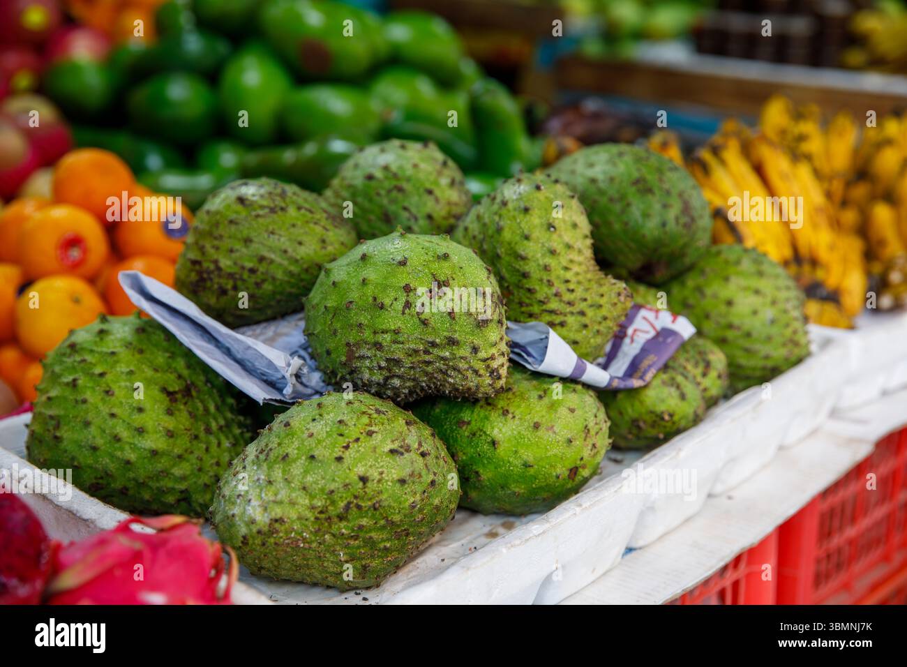 Soursop Guyabano Guanabana Graviola fruits verts exotiques au marché tropical asiatique avec bananes et oranges Banque D'Images