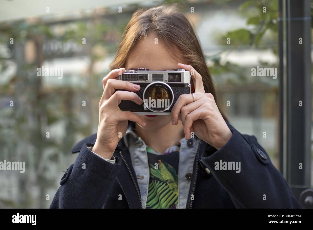 Portrait d'une jeune et jolie de prendre des photos avec l'appareil photo rétro vintage. Street style. Style de vie Banque D'Images
