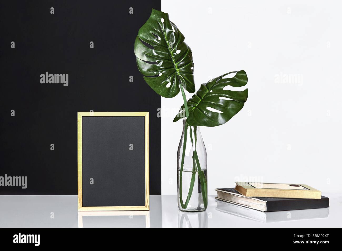 L'intérieur élégant avec maquette affiche, les feuilles dans le flacon en verre sur table avec le noir et blanc mur sur l'arrière-plan. Le minimalisme concept de spa Banque D'Images