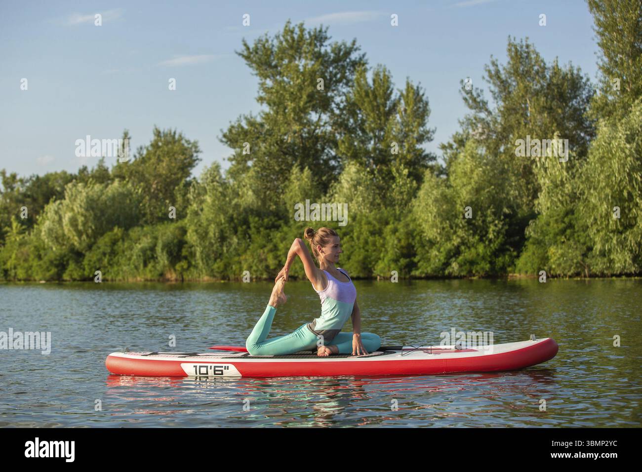 Young woman doing yoga sur conseil du sup avec palettes. Poser méditative, vue latérale - concept de l'harmonie avec la nature, et le mode de vie sain, freelance, Banque D'Images