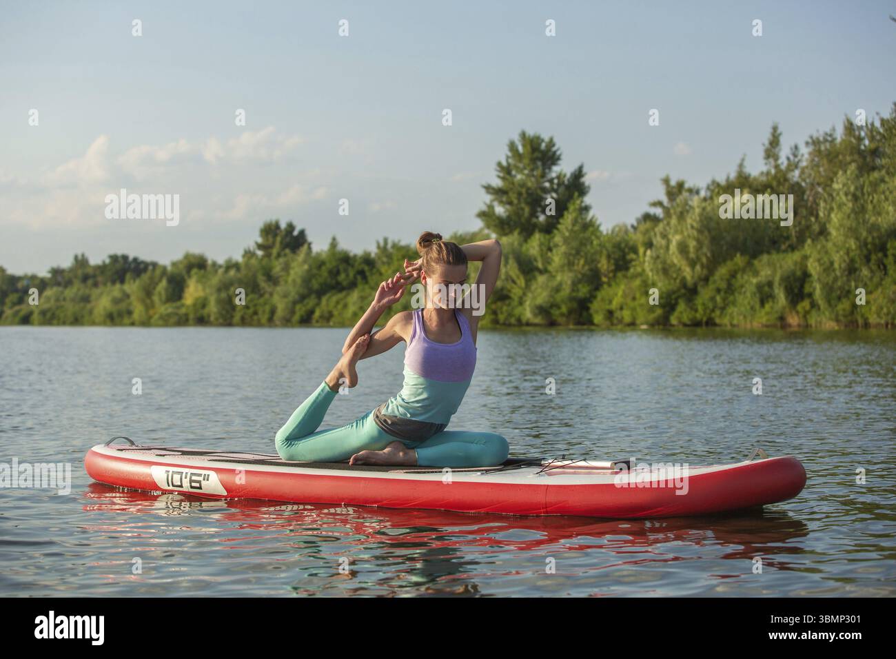 Young woman doing yoga sur conseil du sup avec palettes. Poser méditative, vue latérale - concept de l'harmonie avec la nature, et le mode de vie sain, freelance, Banque D'Images