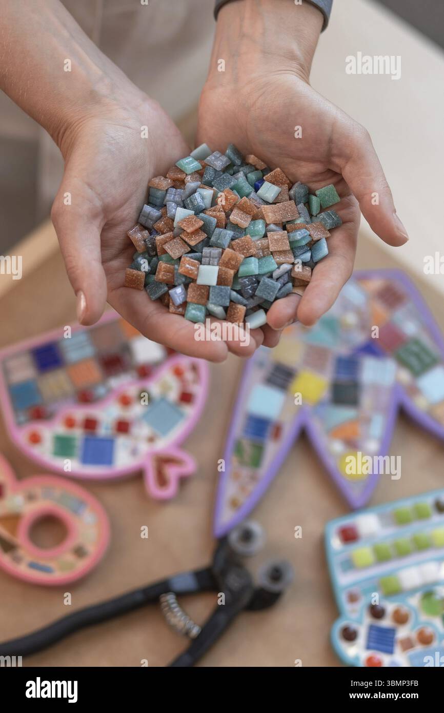 Lieu de travail de la mosaïque maître : women's hands holding détails mosaïque dans le processus de création d'une mosaïque. Close-up Banque D'Images