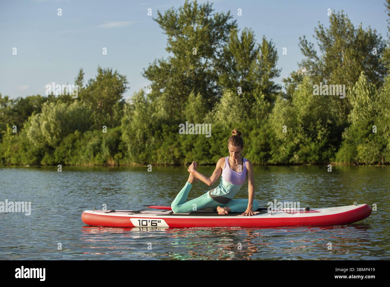 Young woman doing yoga sur conseil du sup avec palettes. Poser méditative, vue latérale - concept de l'harmonie avec la nature, et le mode de vie sain, freelance, Banque D'Images