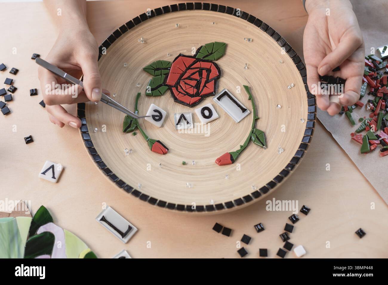 Poste de travail d'un maître de la mosaïque : mise en forme d'un élément de la mosaïque sur la table. Le maître établit sur une plaque en mosaïque fait main de maître Banque D'Images