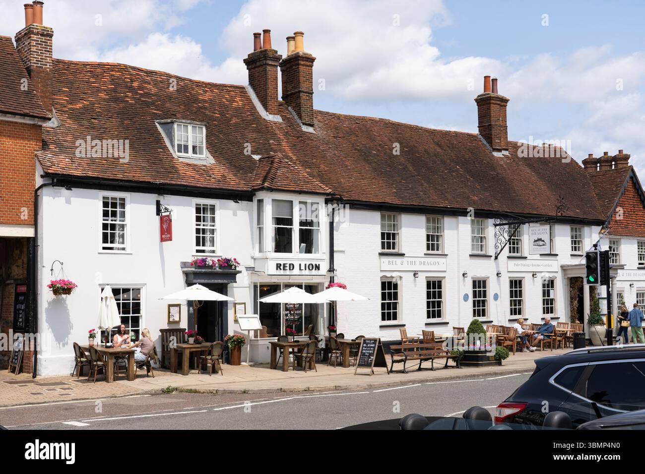 Les gens buvant et mangeant un jour d'été assis devant le pub Red Lion et Bel & the Dragon (George Hotel) sur Odiham High Street, Royaume-Uni Banque D'Images