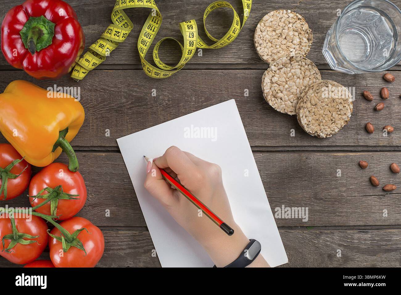 Concept diète, plan amincissant avec légumes vue du dessus maquette. Une main femelle dans un bracelet de sport écrit un article sur la nutrition appropriée Banque D'Images