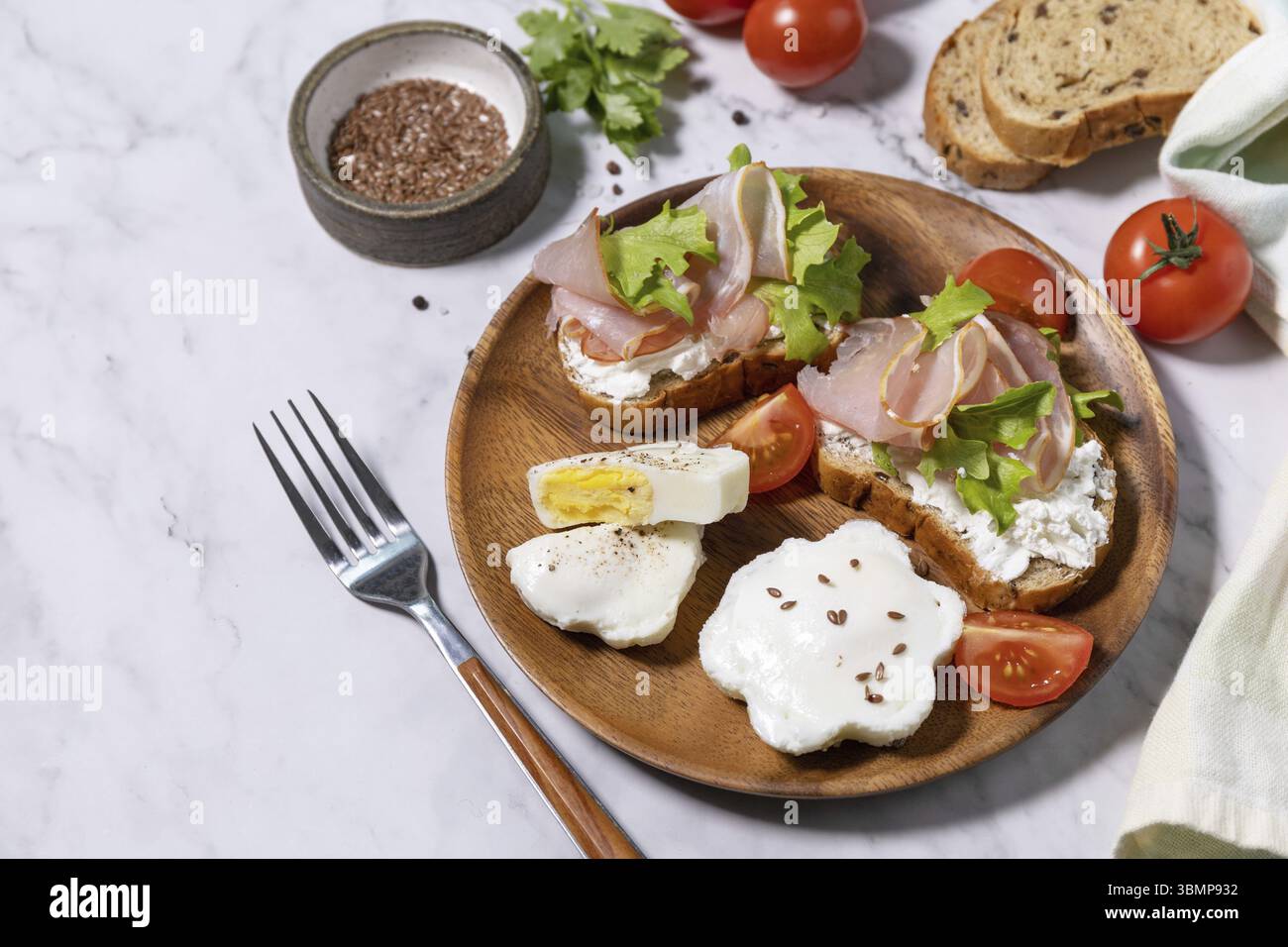 Petit-déjeuner ou brunch de Pâques. Délicieux petit déjeuner ou en-cas - œufs pochés et fromage à la crème pain de seigle complet, prosciutto, arugula sur un t de marbre Banque D'Images